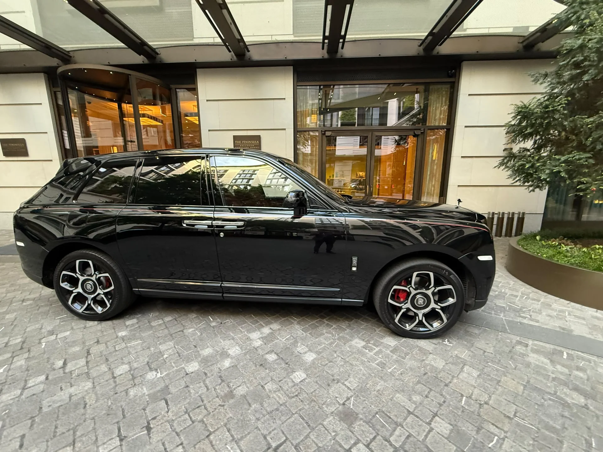 Black Rolls-Royce Cullinan luxury SUV parked at luxury hotel forecourt in London